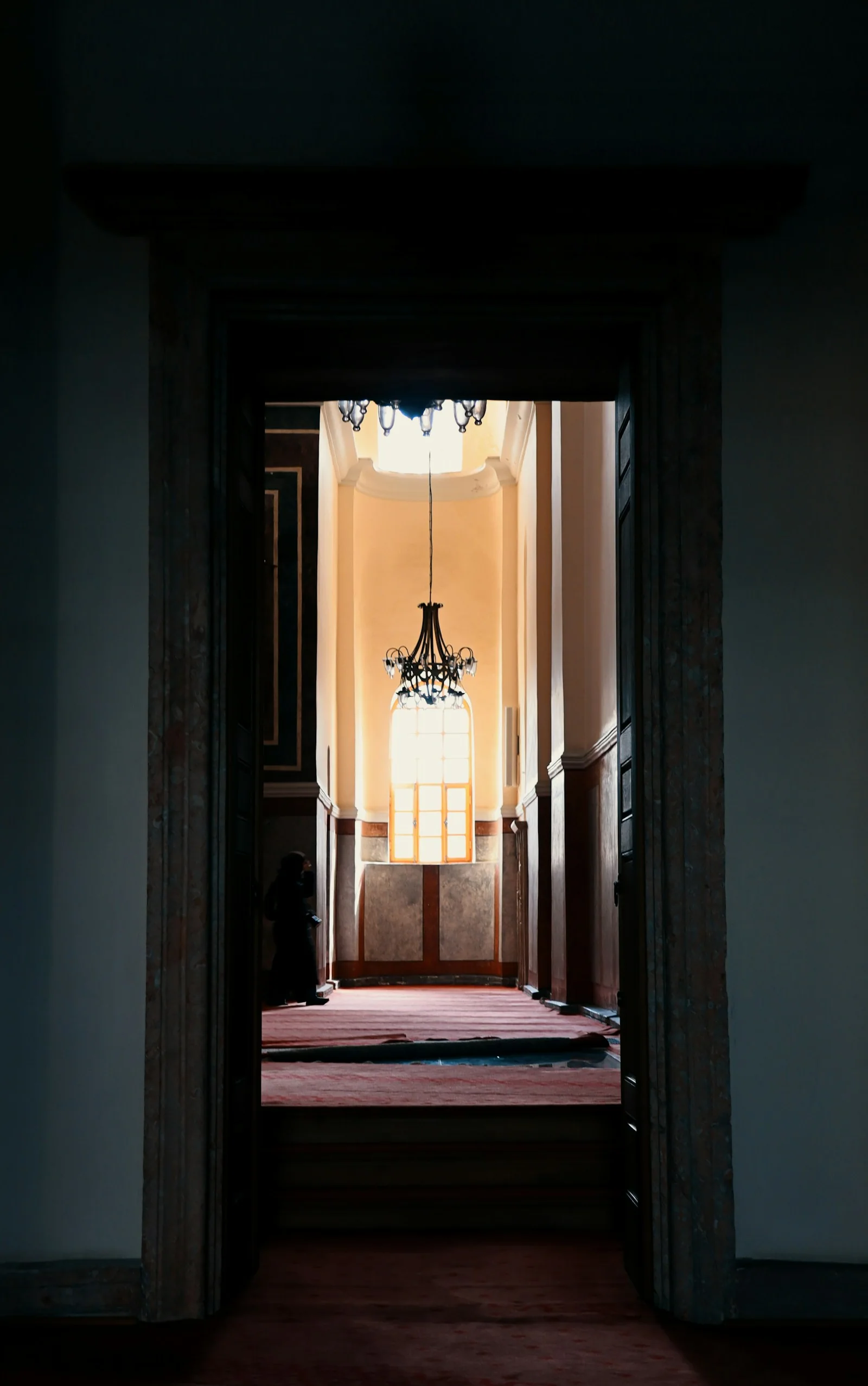A quiet mosque doorway opening onto a sunlit prayer hall