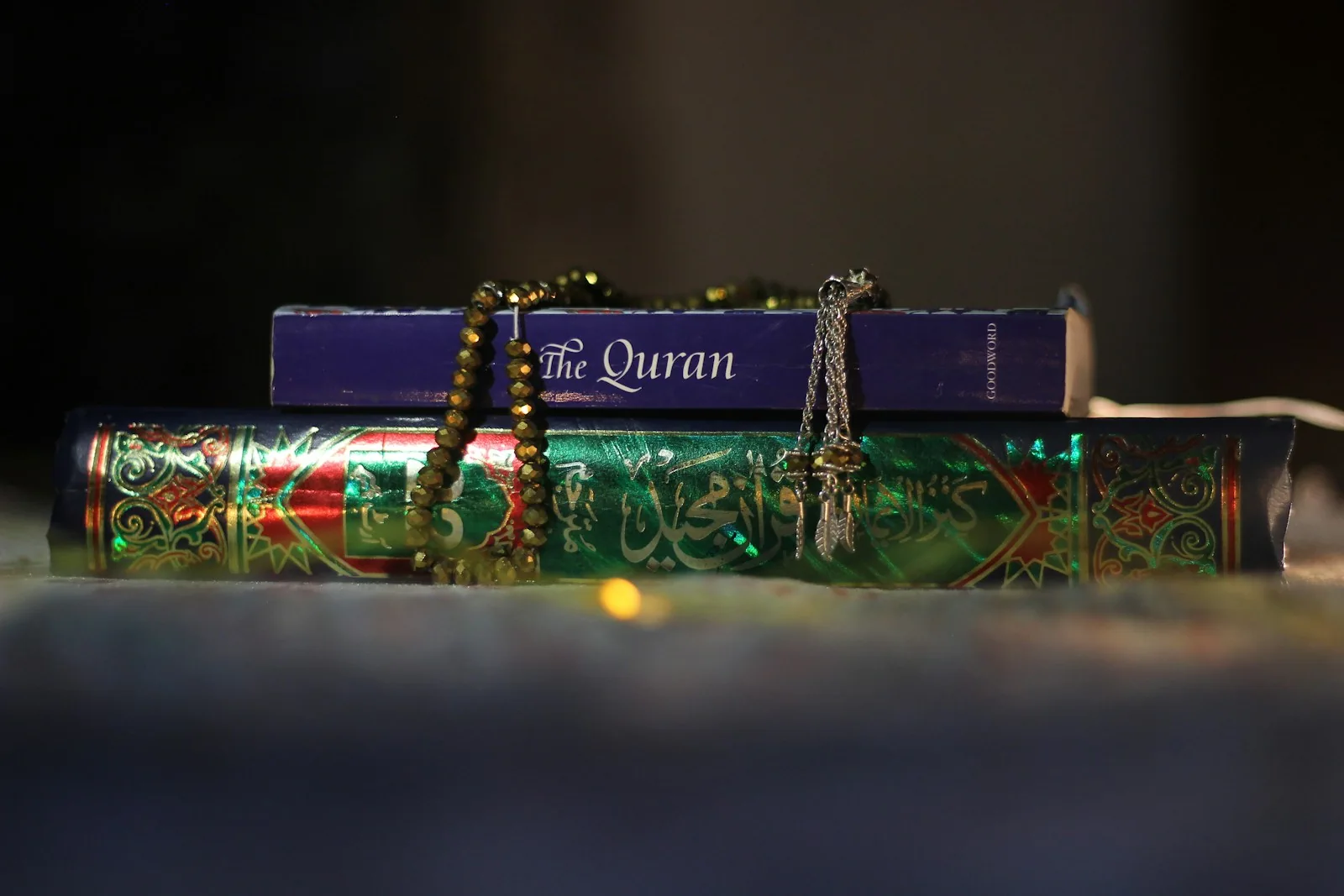 Two copies of the Quran with prayer beads laid over their covers