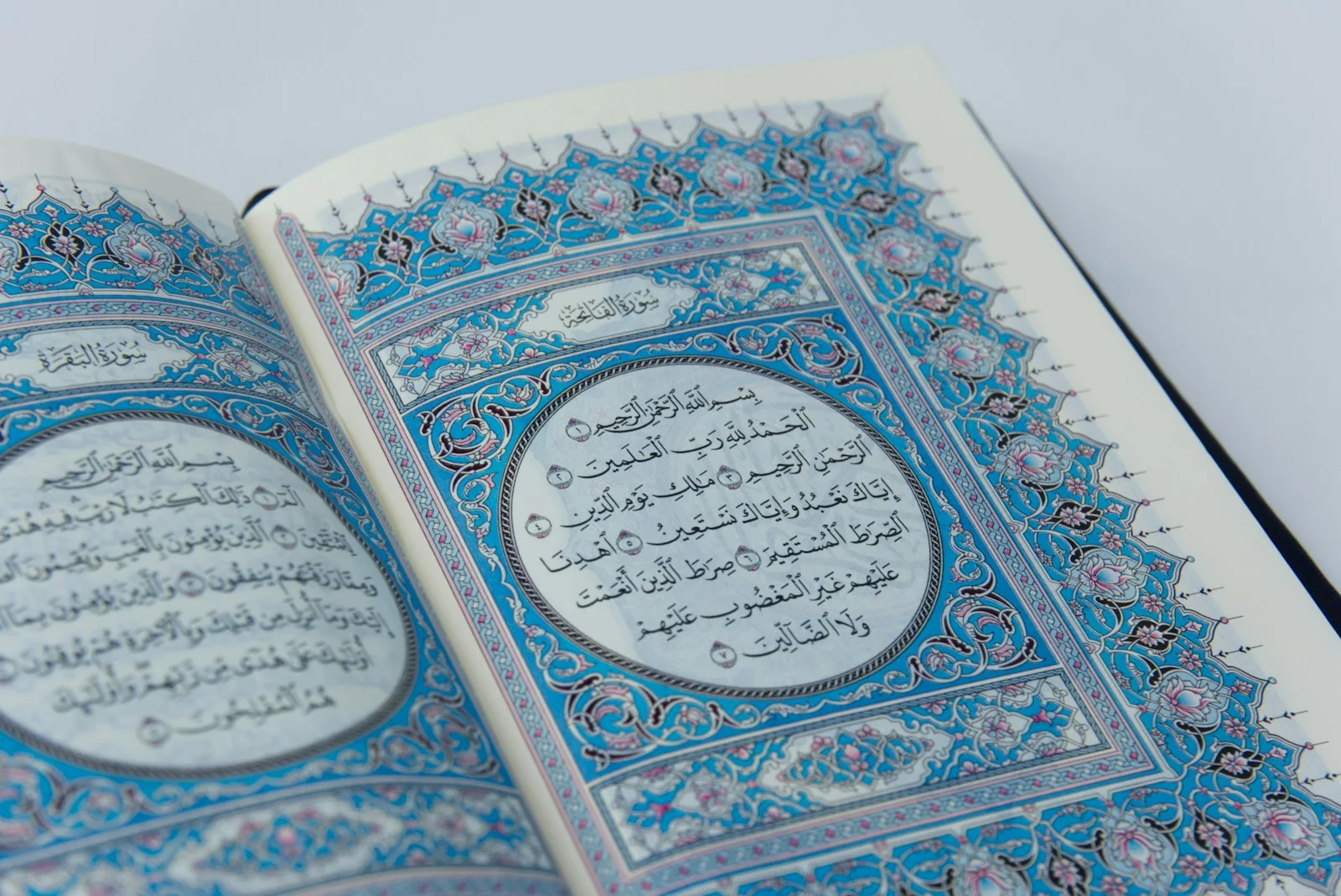 An open Quran showing Al Fatihah inside a blue ornamental border
